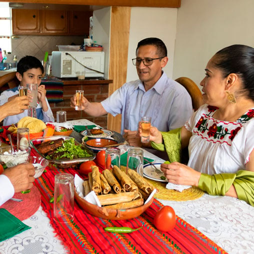 Familia hispana está disfrutando de una cena después de abrir un préstamo para generar crédito con Alianza.