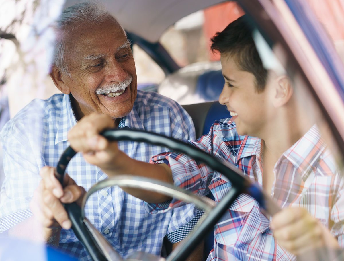 Abuelo enseñando a su nieto a conducir