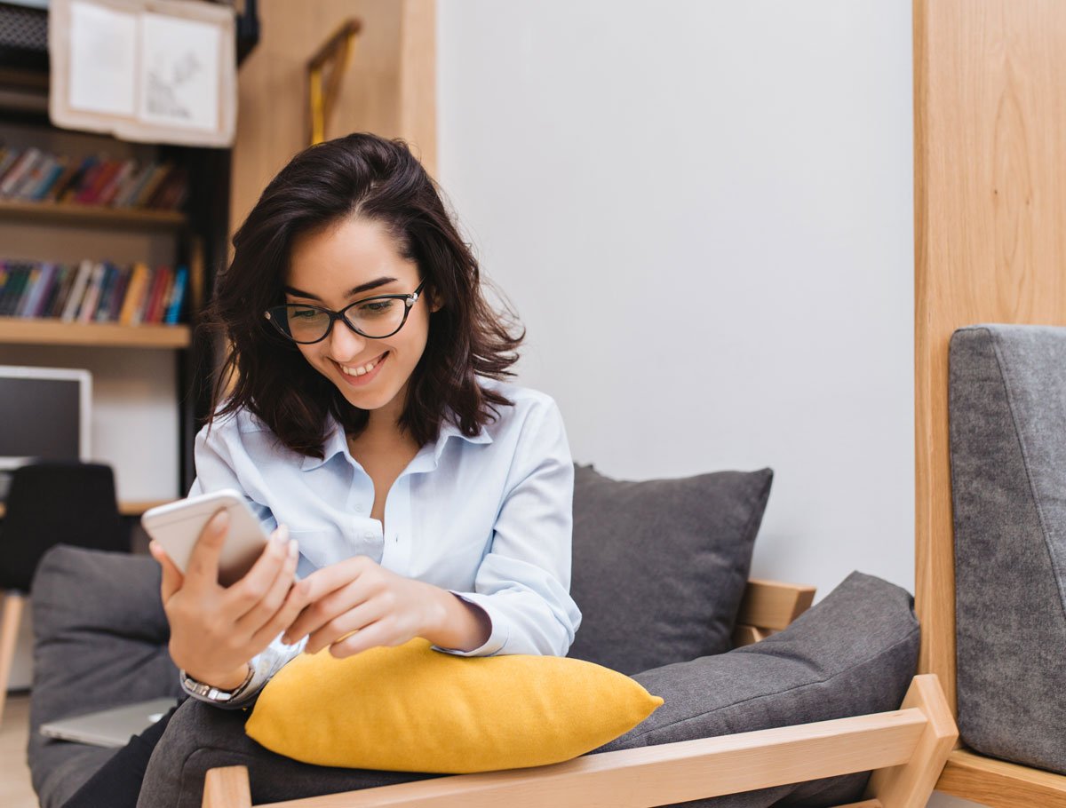 Mujer joven que utiliza la banca móvil de Alianza y la banca en línea en su teléfono celular